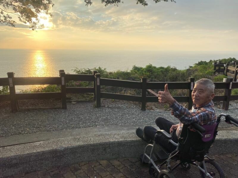 黃水清阿公一輩子務農，沒有看過海。南丁格爾護理之家帶阿公去墾丁旅遊，第一次看到大海開心地比讚。（圖片來源／豐盛集團）