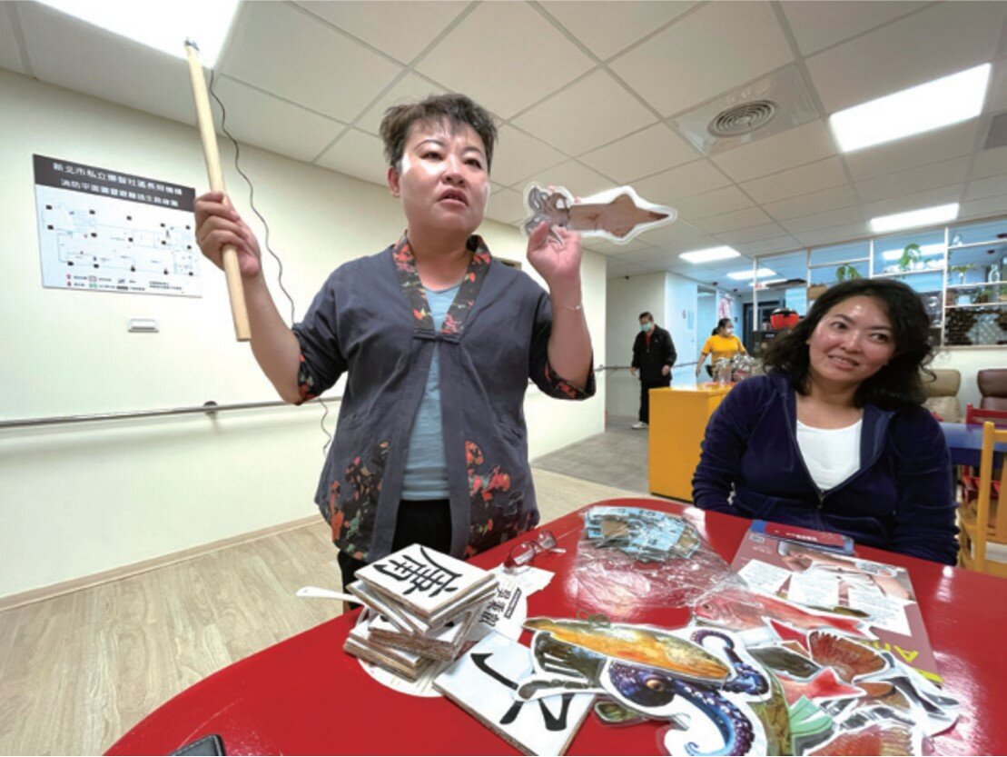 業務負責人李秀涵展示他設計的釣魚遊戲等自製教具。（攝影/戴淨妍）