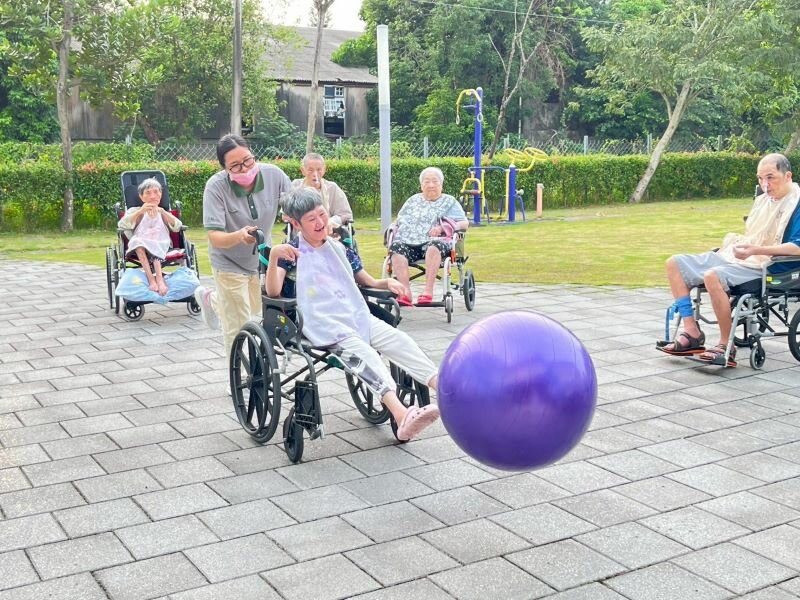 吾老莊的庭院裡，照服員與長輩正在遊戲。（照片提供_大愛長照體系）