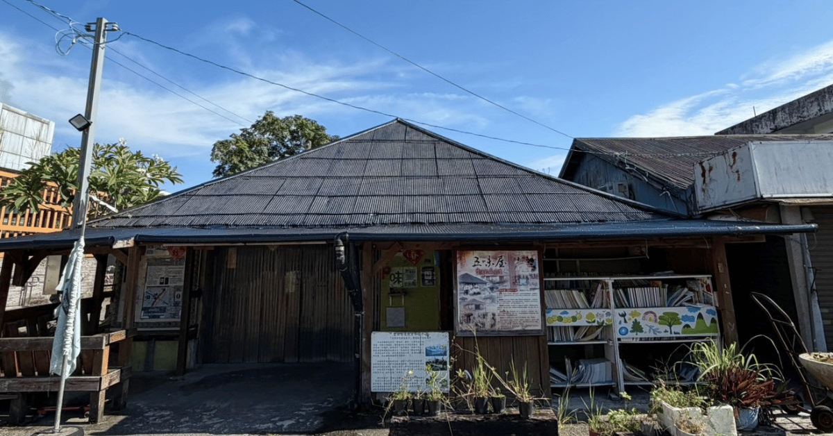 五味屋懸掛的彩繪布畫，以酸、甜、苦、辣、鹹呈現人生五味，搭配老屋、綠葉、愛心、樹木與辣椒圖案。