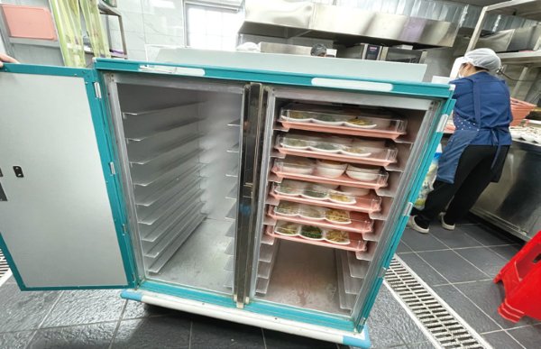 中午時分，廚師將飯菜放入航空級保溫餐車。(圖片來源/馨安長照)